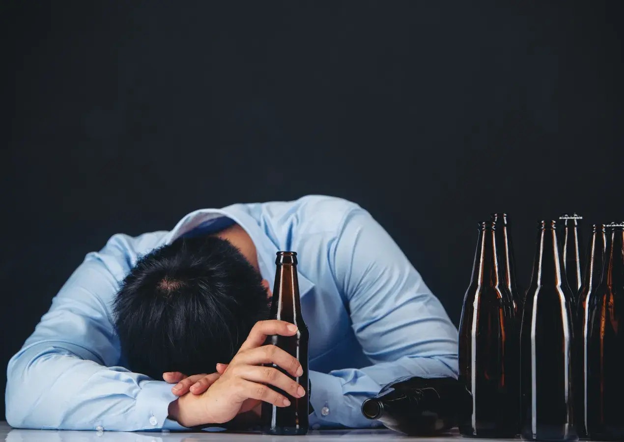 Un homme dort près de bouteilles d'alcool.