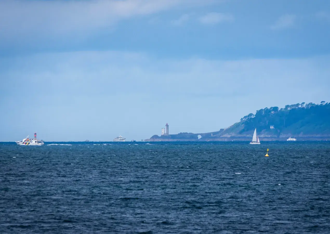 Large vue sur un océan avec un phare au loin.