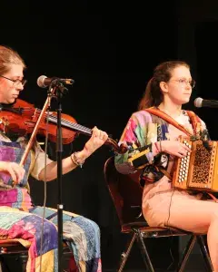 Photo montrant 2 musiciennes jouant en concert sur une scène du violon traditionnel et de l'accordéon diatonique