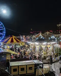 Photo montrant un village de Noël illuminé à la nuit tombée 