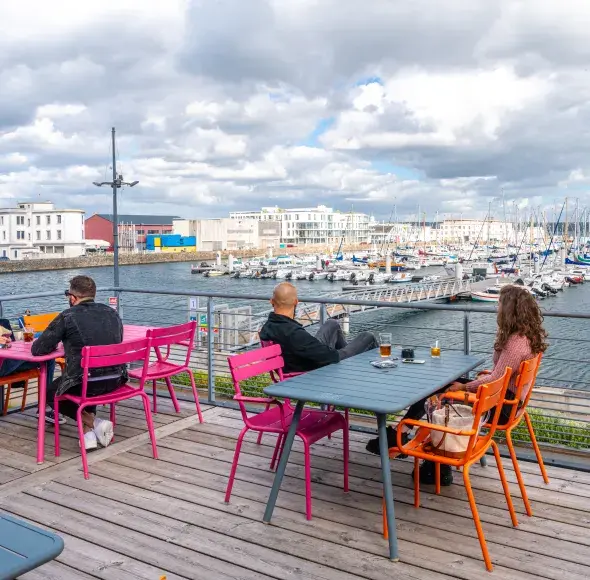 Des personnes en terrasse devant le port du Château