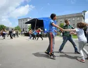 Des enfants en train de danser au milieu d'une place.