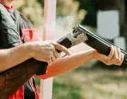 Un homme tient un fusil de chasse. 