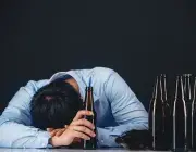 Un homme dort près de bouteilles d'alcool.