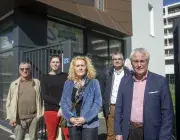 Plusieurs personnes posent devant un bâtiment. 