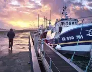 une silhouette sur la digue Lapérouse et un bateau de pêche