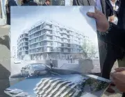 Une personne tient deux affiches de projets immobiliers.
