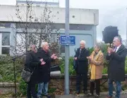 Plusieurs personnes devant une plaque de rue.