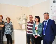 Des hommes et des femmes posent devant une sculpture