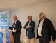 Trois hommes parlent devant un pupitre.