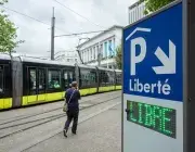 Un homme passe devant le tram, à proximité du panneau d'accès au parking couvert de la place de la Liberté