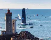 Un bateau géant passe devant un phare. 