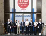 Plusieurs personnes coupent un ruban devant une grande porte.