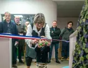 Une femme coupe un ruban à côté d'une petite fille.