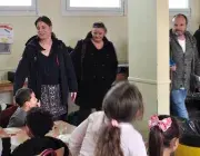 Des enfants assis à la cantine et des adultes autour leur parlant