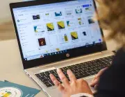 Une femme de dos entre des informations dans un ordinateur.