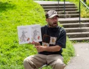Un homme lit un livre au pied d'une tour.