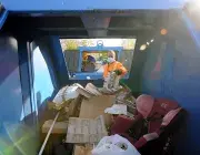 Un homme jette quelque chose dans une benne.