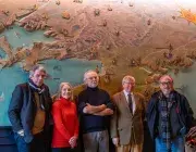 Plusieurs personnes posent devant une grande fresque.