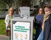 Trois personnes à côté d'un container à poubelles.