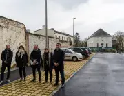 Plusieurs personnes posent sur un parking. 