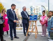Des adultes et des enfants dévoilent une plaque.