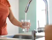 Une femme se sert un verre d'eau au robinet