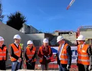 des hommes et des femmes posent la première pierre de la station d'ascenseurs urbains du CHU. 