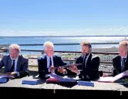 Des hommes signent un document officiel sur le parvis de la gare de Brest, au-dessus du port