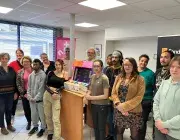 Des femmes et des hommes posent devant une borne d'arcade