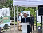 Un homme au micro, devant une exposition en plein air 