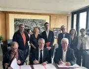 3 hommes derrière un bureau signent un partenariat.