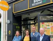 deux hommes et deux femmes posent devant un restaurant