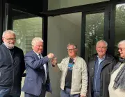 deux hommes échangent des clés devant le local associatif de Quéliverzan