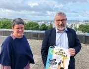 Un homme et une femme posent avec l'affiche de l'opération des Lieux à réinventer de la ville de Brest. 