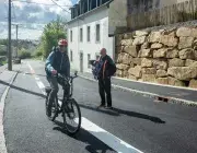 Un cycliste et un piéton se croisent sur une route. 
