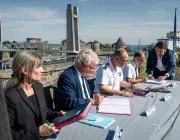 Des hommes et des femmes signent des parapheurs à proximité de la Penfeld