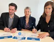 Un homme et deux femmes signent une charte d'engagement. 