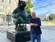 Philippe Geluck debout devant une de ses statues du Chat.