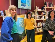 Trois femmes debout devant une affiche du festival