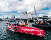 Un hommes les bras levé sur son aviron de mer arrivant au port de Brest devant une foule sur le quai