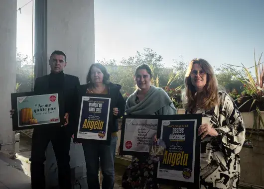 Quatre personnes tiennent des affiches.