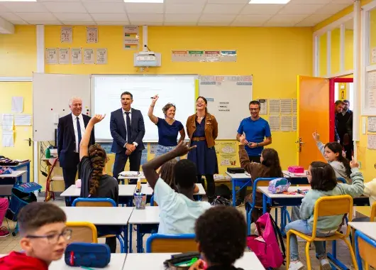Cinq personnes debout devant le tableau du salle de classe.