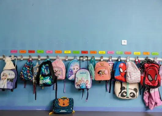 Des cartables d'écoliers accrochés au porte-manteaux. 