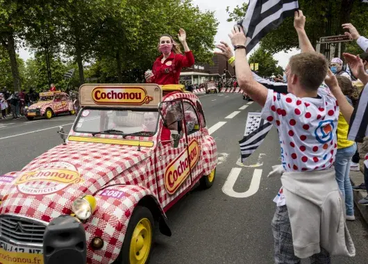 Des spectateurs applaudissent une voiture qui passe. 