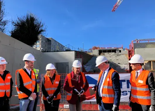 des hommes et des femmes posent la première pierre de la station d'ascenseurs urbains du CHU. 