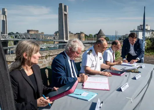 Des hommes et des femmes signent des parapheurs à proximité de la Penfeld