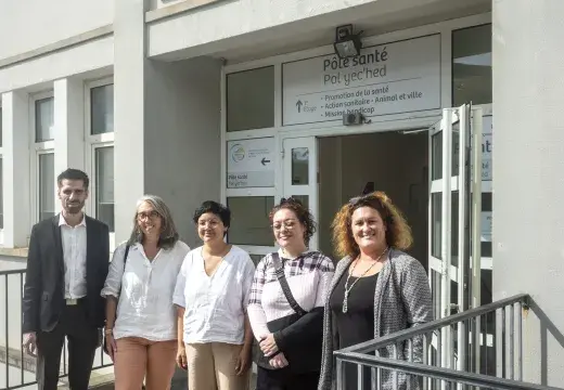 Plusieurs personnes posent devant un bâtiment. 