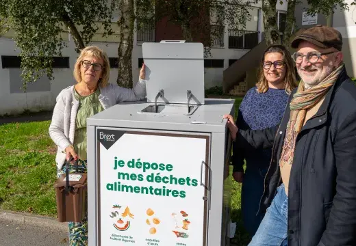 Trois personnes à côté d'un container à poubelles.
