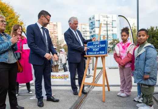Des adultes et des enfants dévoilent une plaque.